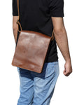 Elegant brown leather messenger bag placed on a wooden desk