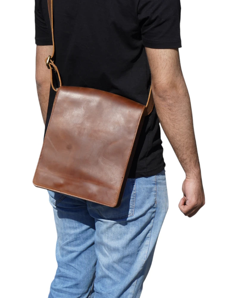 Elegant brown leather messenger bag placed on a wooden desk