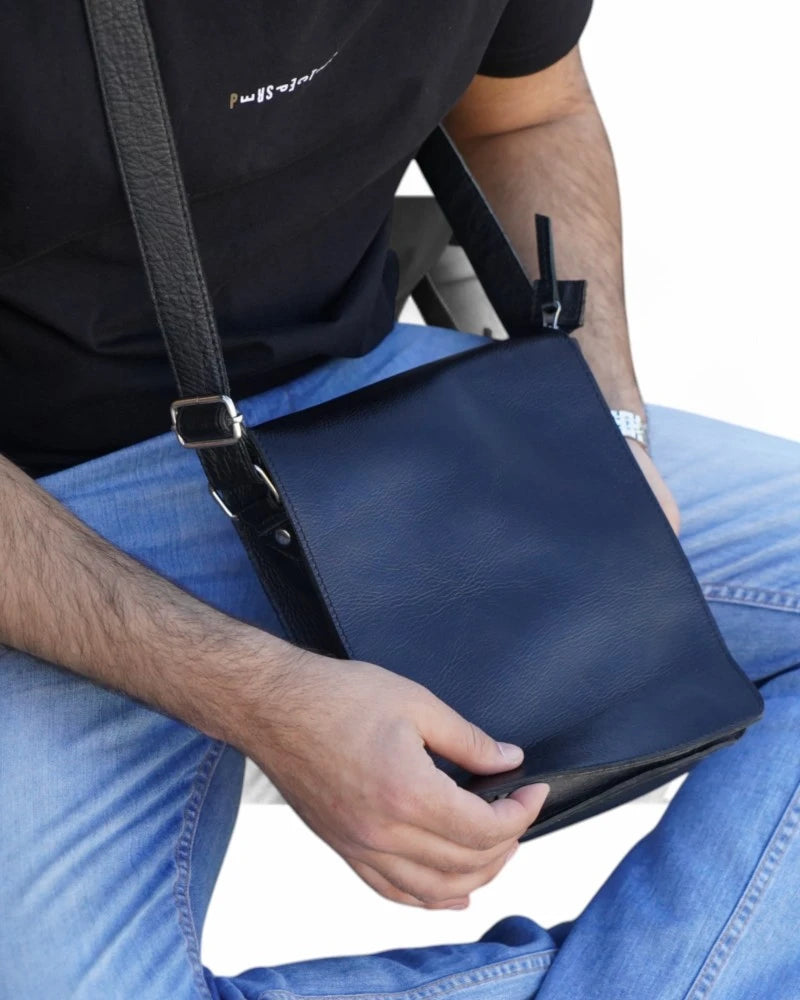 Side profile of a black leather messenger bag with buckle closure