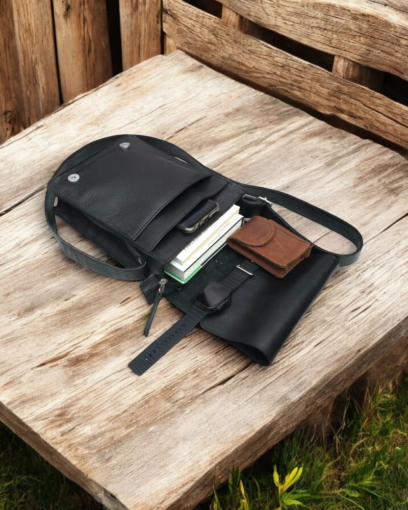 Back view of a black leather messenger bag with zippered pocket