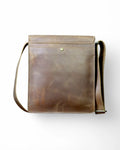 Adjustable leather strap detail on a brown leather messenger bag