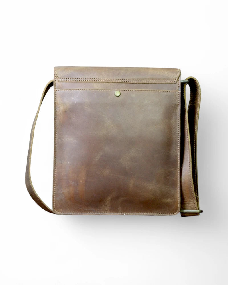 Adjustable leather strap detail on a brown leather messenger bag