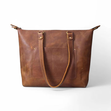 Close-up of full-grain leather laptop tote bag showcasing rich texture and fine stitching.

